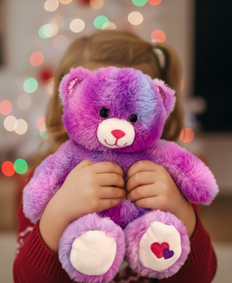 Child holding a purple teddy bear with a blurred Christmas tree in the background