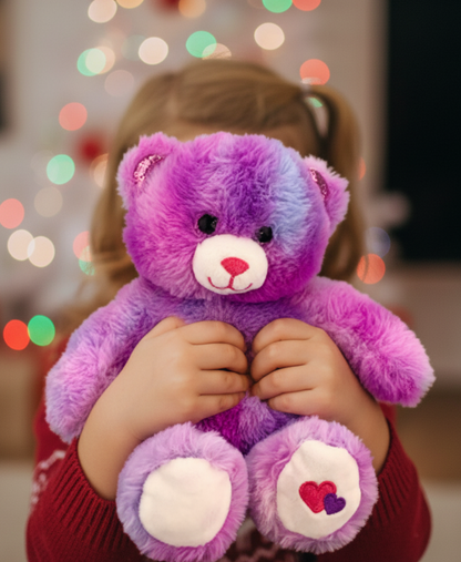 Child holding a purple teddy bear with a blurred Christmas tree in the background