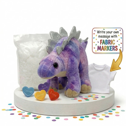 Purple dinosaur plush toy with fabric markers and a shirt on a white base with colorful confetti.